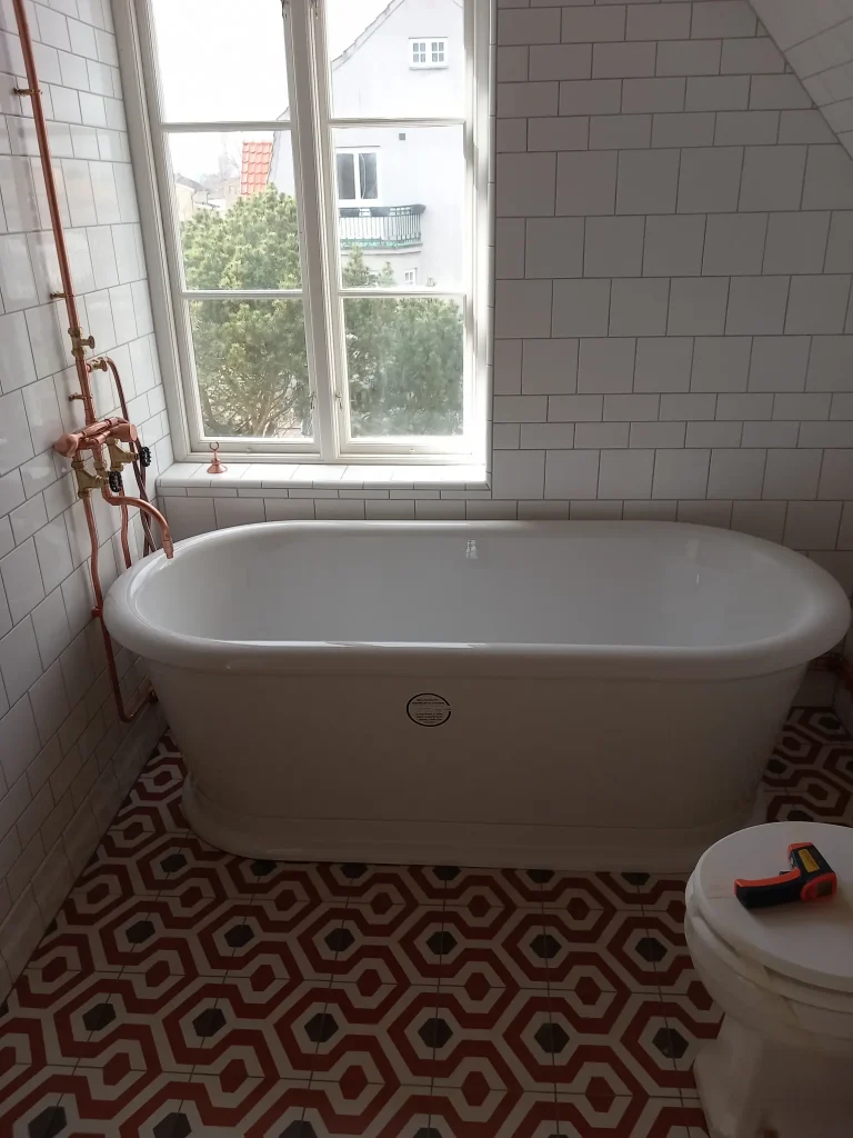 Färgstark badrumsrenovering med fristående badkar och mönstrat klinkergolv i mexikansk stil.